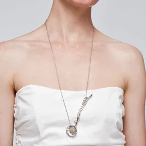 Detailweergave van een minimalistische zilveren madeliefje ketting gedragen door model