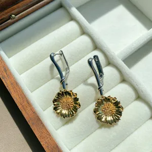 Close-up van elegante goud- en zilverkleurige madeliefjes oorbellen in een doosje.