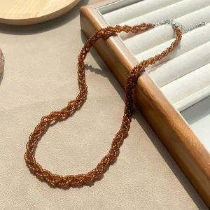 Detailansicht einer dreisträngigen bernsteinfarbenen Perlenkette auf einem Schmucktablett aus Holz