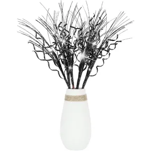Close-up of black glittery curly branches with sparkling lights in white vase