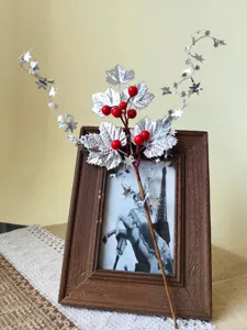 Detail of Christmas decoration stem with silver maple leaves, red berries, and stars