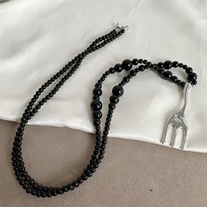 Macro shot of a niche black bead necklace featuring a creative silver fork pendant detail.