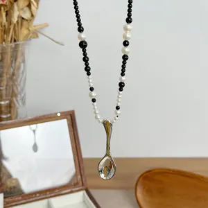 Close-up of a creative silver spoon pendant necklace with black and white beads.