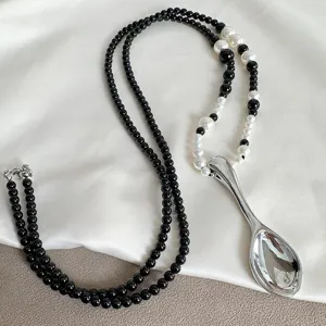 Macro detail of creative silver spoon pendant necklace with black and white beads