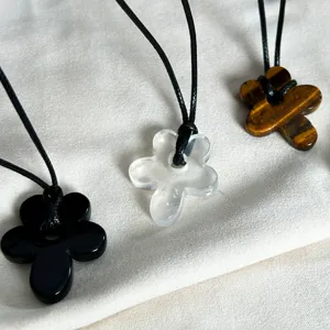 Detail of three flower necklaces in black, clear, and tiger eye stone with cords.