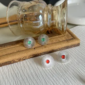 Dettaglio degli orecchini a margherita in argento con pietre preziose verdi e rosse