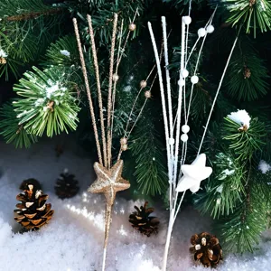 Nahaufnahme goldener und weißer Stern-Dekopicks in einer verschneiten Kiefernumgebung