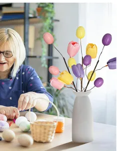 Detailansicht bunter Oster-Tulpen- und gesprenkelter Eierzweige in einer weißen Vase