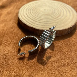 Orecchini a cerchio color argento con motivo a spirale a coste su legno naturale