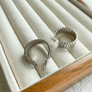 Dettaglio di orecchini a cerchio vintage color argento con strisce a spirale