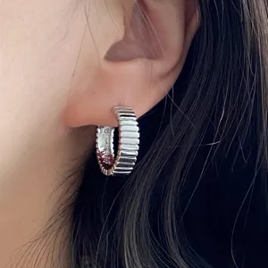 Dettaglio ravvicinato di orecchino a cerchio argento con texture a spirale retrò