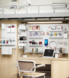 Detailed view of white DIY pegboard wall organizer system on a dormitory desk