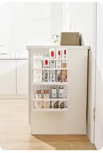 Detail view of white plastic pegboard kitchen rack mounted on cabinet side holding bottles