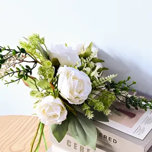 Vue détaillée d'un bouquet de mariée de roses blanches artificielles avec eucalyptus.