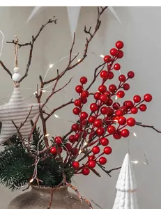 Close-up of vibrant red artificial berries with warm LED string lights and festive Christmas decor