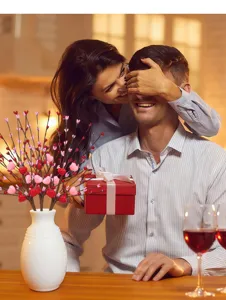 Dettaglio decorativo ramo cuore San Valentino con scena romantica, vaso e regalo.