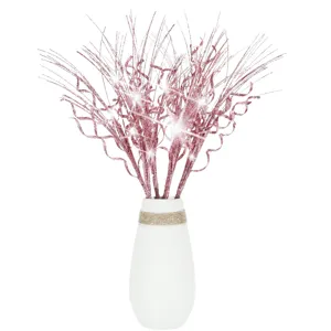 Close-up of pink glitter curly spray branches arranged in a minimalist white ceramic vase