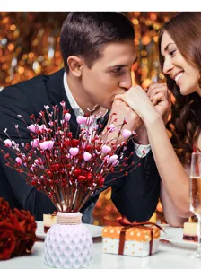 Romantic Valentine's Day dinner scene featuring red and pink heart berry stems in a white vase