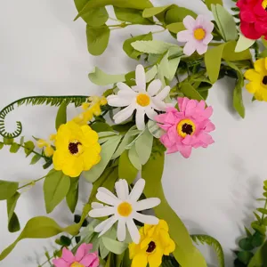 Artificial flower wreath detail close up featuring colorful daisies and lush green leaves for home decor