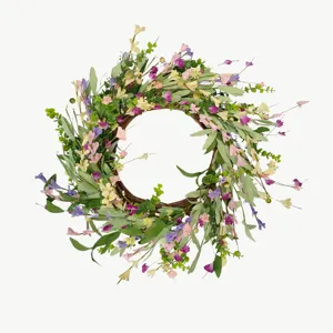 Detailweergave van een lentekrans met roze en paarse wilde bloemen op een wijnstokbasis.