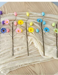 Detailed view of colorful Easter speckled egg and daisy floral picks on a rustic cloth