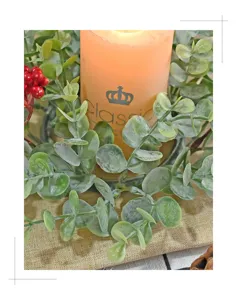 Close-up detail of artificial eucalyptus and red berry candle ring decoration