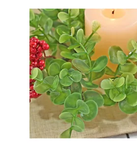 Close-up of artificial eucalyptus and red berries for Christmas candle ring decoration.