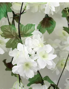 Détail des pétales de fleurs de cerisier artificielles blanches et feuilles vertes
