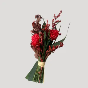 Gros plan detail du bouquet de fleurs sechees preservees rouges avec feuilles vertes et ficelle.