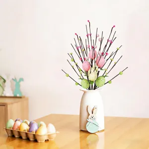 Artificial Easter egg and berry branches in a white vase for holiday table decoration.