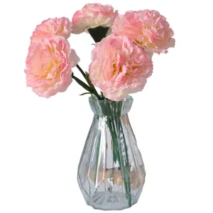 Claveles artificiales rosas en un jarrón de cristal facetado para casa