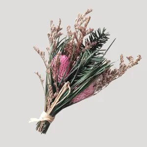 Vue détaillée du petit bouquet de fleurs séchées avec accents roses et feuillage vert.