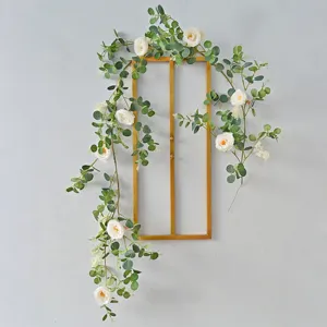 Beautiful artificial eucalyptus and white rose vine draped on a gold metal wall frame