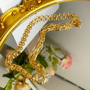 Detailed macro view of vintage golden Roman link chain necklace on a mirror