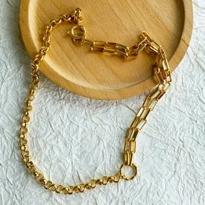 Detail view of a vintage gold mixed link chain necklace on a wooden tray background