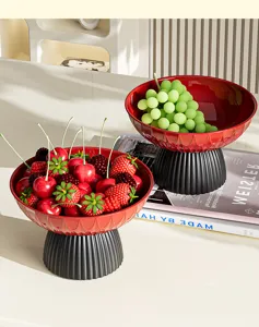 Frutero circular moderno de pie alto con fresas y uvas frescas en primer plano