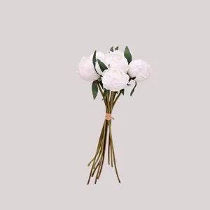 Detail of white artificial peony bouquet showing realistic flower buds and green leaves.