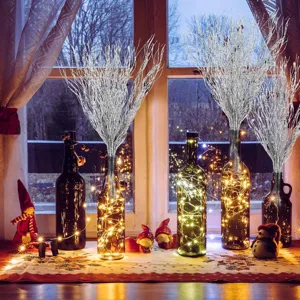 Christmas twig branches in glowing glass bottles with festive table decor for holiday scenes.