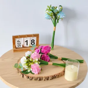 Close-up detail of pink and blue artificial rose bouquets on a wooden table arrangement