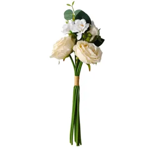 Close-up of artificial rose and camellia bouquet with green leaves tied with twine