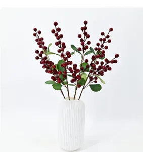 Detailed view of artificial red berry branches in a textured white ceramic vase