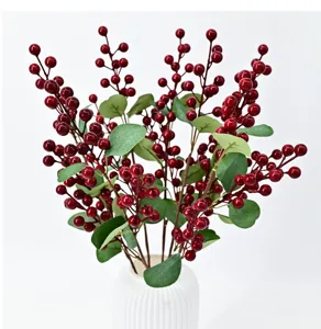 Detail of artificial red berry stems with green leaves in a white vase for home decor
