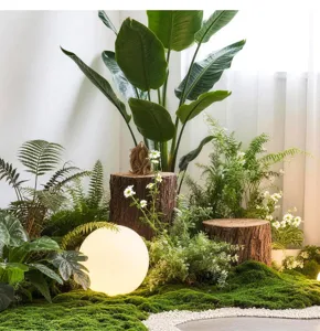 Detailed view of artificial moss turf and green plant landscaping setup with natural tree stumps.