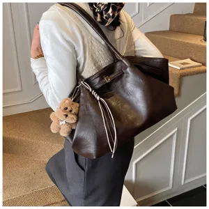 Dettaglio di una grande borsa tote vintage in pelle marrone con ciondolo a orsetto
