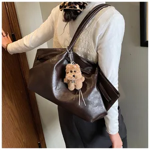 Dettaglio di una grande borsa tote marrone vintage con un simpatico ciondolo a forma di cane