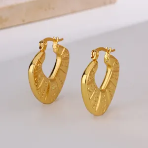 Gros plan détaillé de boucles d'oreilles créoles cœur dorées avec un motif texturé