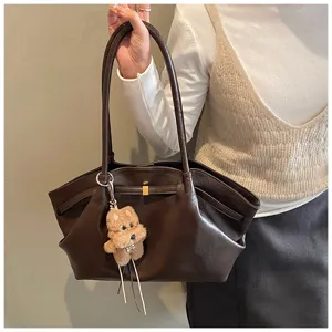 Vista dettagliata di una borsa tote retrò marrone con ciondolo a cucciolo.
