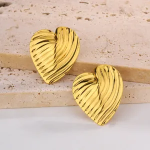 Vue détaillée de boucles d'oreilles cœur dorées avec une surface texturée élégante.