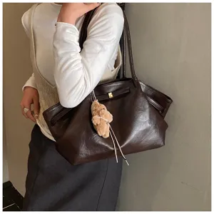 Dettaglio di una grande borsa tote marrone vintage con un simpatico ciondolo a orso