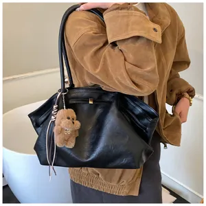 Modello con una grande borsa sottobraccio nera retrò e ciondolo a forma di cane